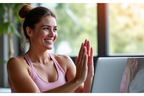 Mulher sorrindo assistindo a um vídeo tutorial de exercícios em seu laptop, em um ambiente de sala de estar convidativo.